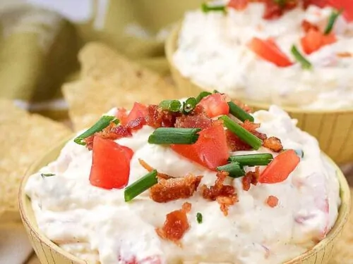 A close-up picture of the finished blt dip in yellow bowls, served with tortilla chips.