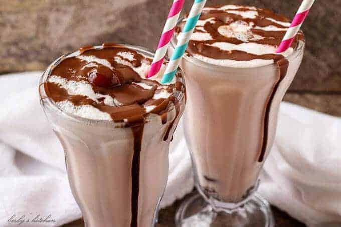 The finished chocolate covered cherry milkshake recipe in soda glasses, smothered in chocolate sauce.