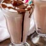 A final shot of the finished chocolate covered cherry milkshakes in glasses with straws and smothered with chocolate sauce.