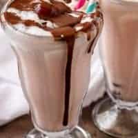 A final shot of the finished chocolate covered cherry milkshakes in glasses with straws and smothered with chocolate sauce.