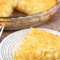 Close up photo of a slice of coconut custard pie with a pie dish in the background.