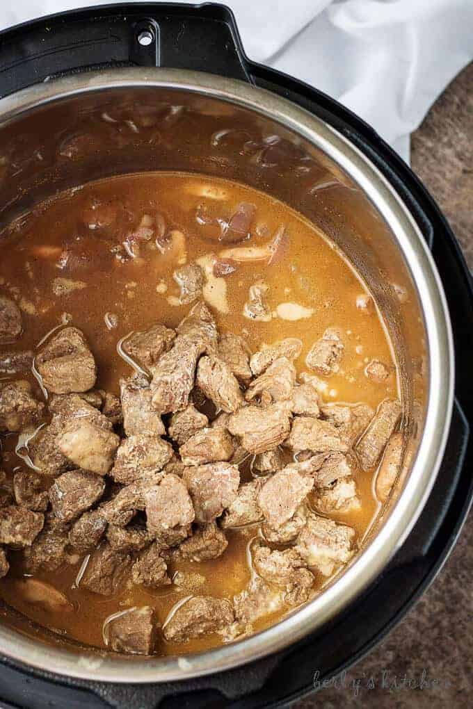 Ariel view of cooked sirloin, onions, mushrooms, beef broth, and red wine in an instant pot.