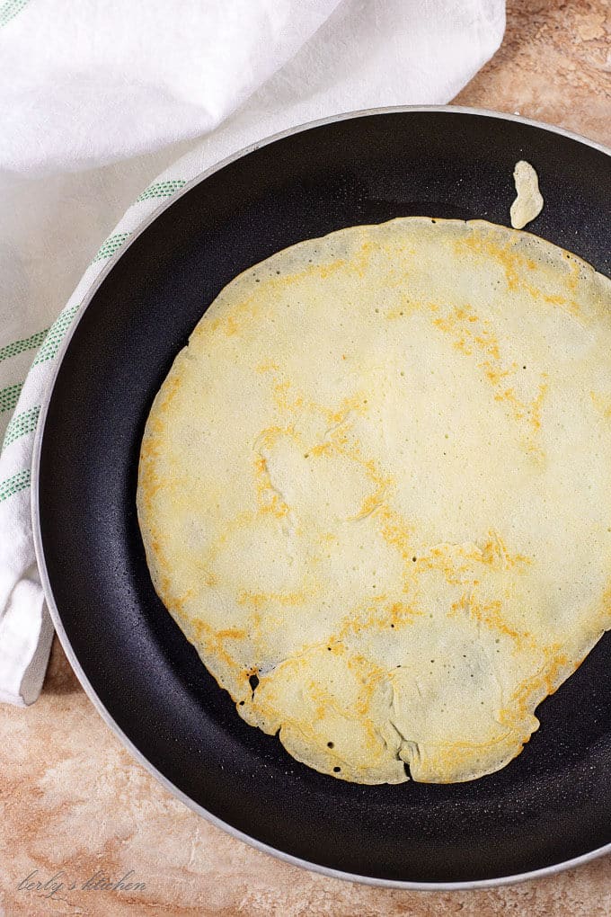 A top-down view of a gluten free crepe cooking in the non-stick pan.