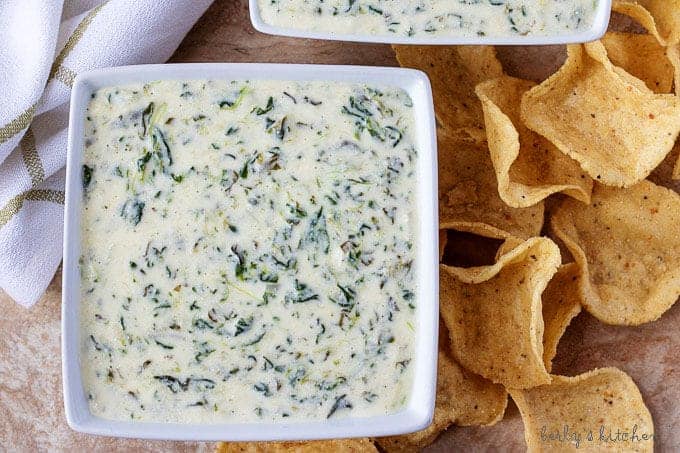 Ariel view of two square bowls of Instant Pot Hot Spinach Dip with tortilla chips