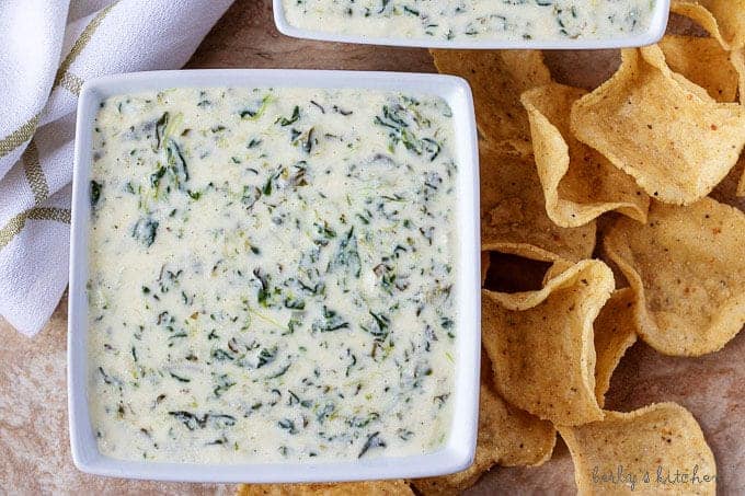 Ariel view of two square bowls of instant pot hot spinach dip with tortilla chips