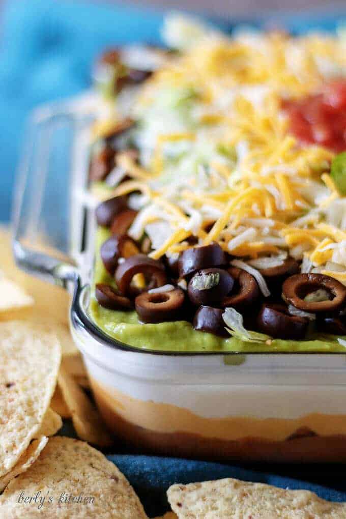 A close-up view of the 7 layer dip in which all the layers can be seen in the clear glass baking dish.