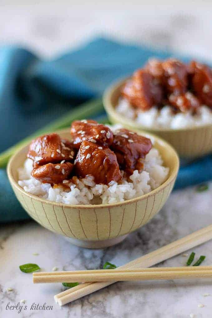 A close-up photo of the finished mongolian chicken in bowls with blue towels and chopsticks.