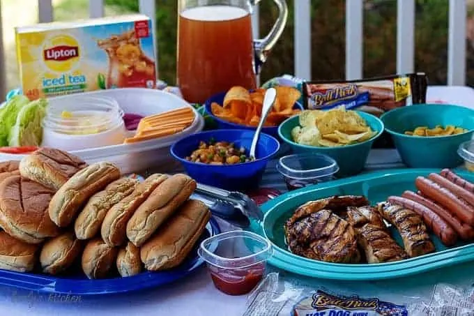The finished backyard bash table setting with chicken breast, hot dogs, and iced tea.