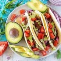 Ariel view of three shredded beef tacos on a plate.