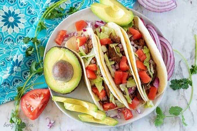 Ariel view of three shredded beef tacos on a plate.