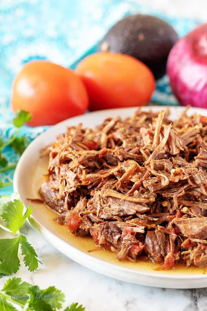 A plate of shredded beef and tomatoes used to fill shredded beef tacos.