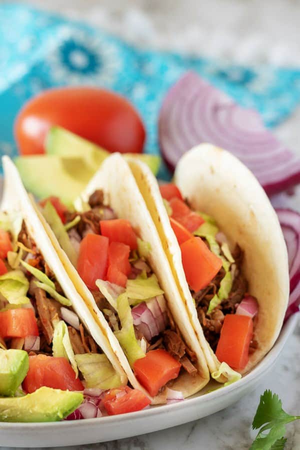 Shredded beef tacos on a grey plate used for Pinterest.