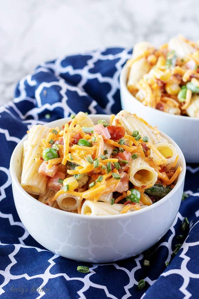 Another picture of the finished cold pasta salad served in white bowls atop a blue towel.