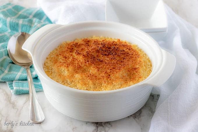 The funeral potatoes, topped with toasted breadcrumbs, in white serving dish.