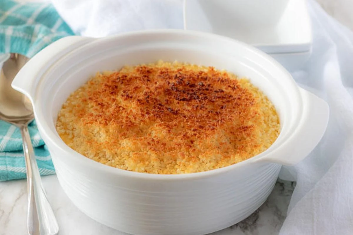 The funeral potatoes, topped with toasted breadcrumbs, in white serving dish.