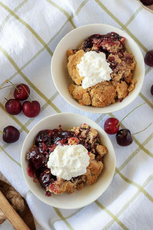 An aerial photo of the cherry crisp topped with whipped cream.