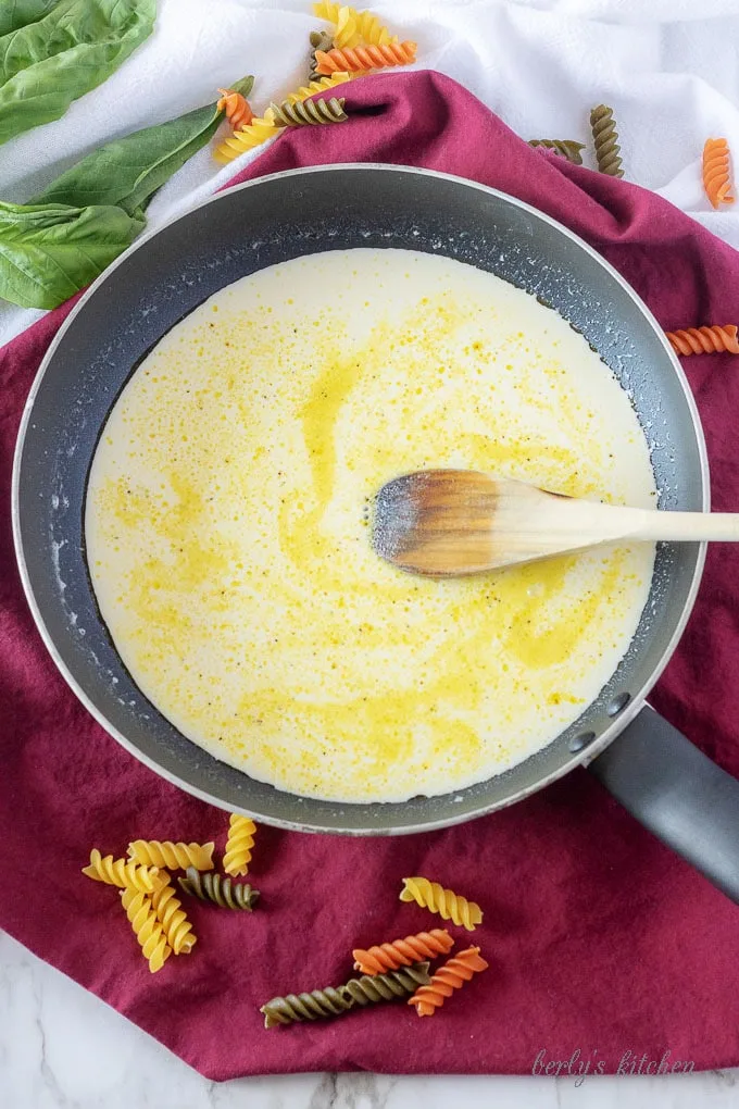 The lemon cream sauce cooking in a saute pan before the olive oil and heavy cream has completely mixed.