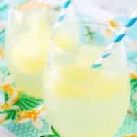 The tropical cocktail booze cubes melting in the sparkling water served in a stemless wine glass.