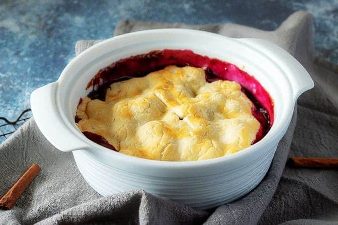The finished berry cobbler in a white casserole dish, ready to be served.