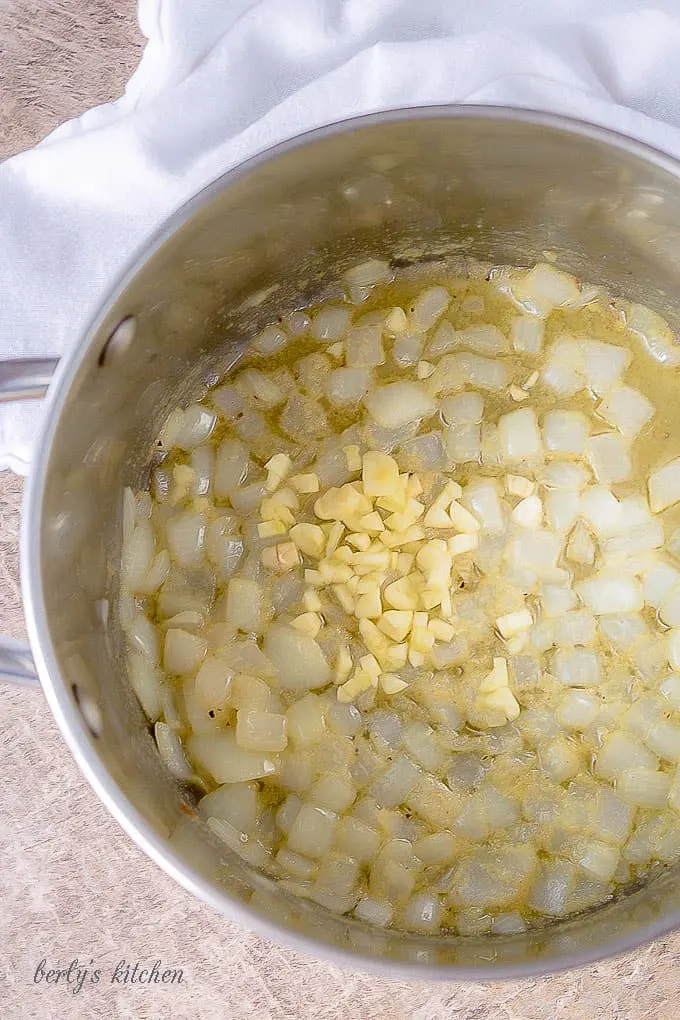 Ariel view of onions, garlic, seasonings, and melted butter in a stock pot for broccoli cheese soup.