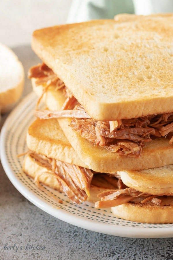 A large picture of two pulled pork sandwiches on toasted white bread.