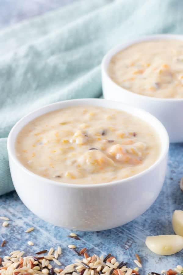 The finished mushroom soup served in white bowls sitting on a blue kitchen towel.