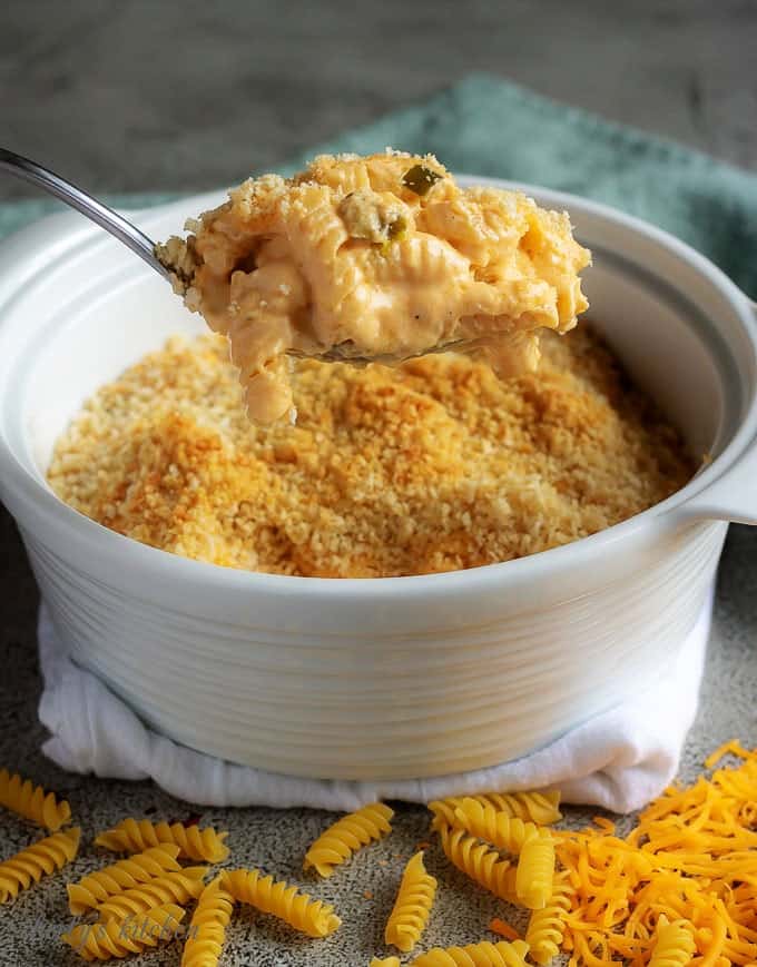 A close-up photo of the baked macaroni and cheese, cooked, and being scooped out of the white baking dish.