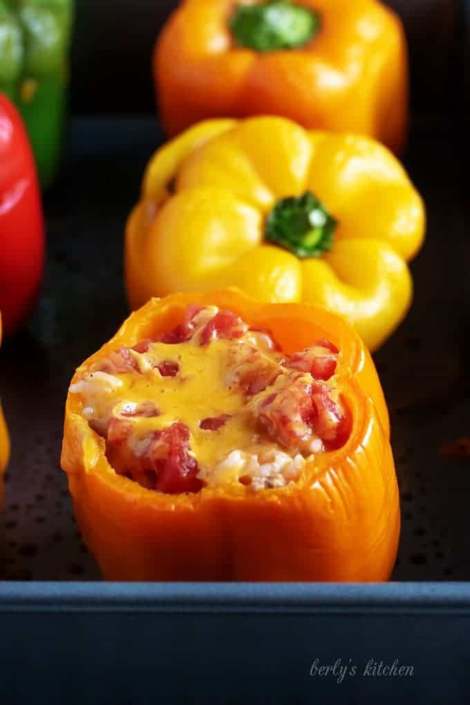 Cooked ground turkey stuffed peppers covered with melted cheese and tomatoes.