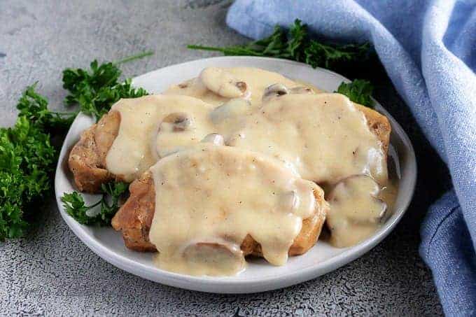 Instant pot pork chops with mushroom gravy on a gray plate.