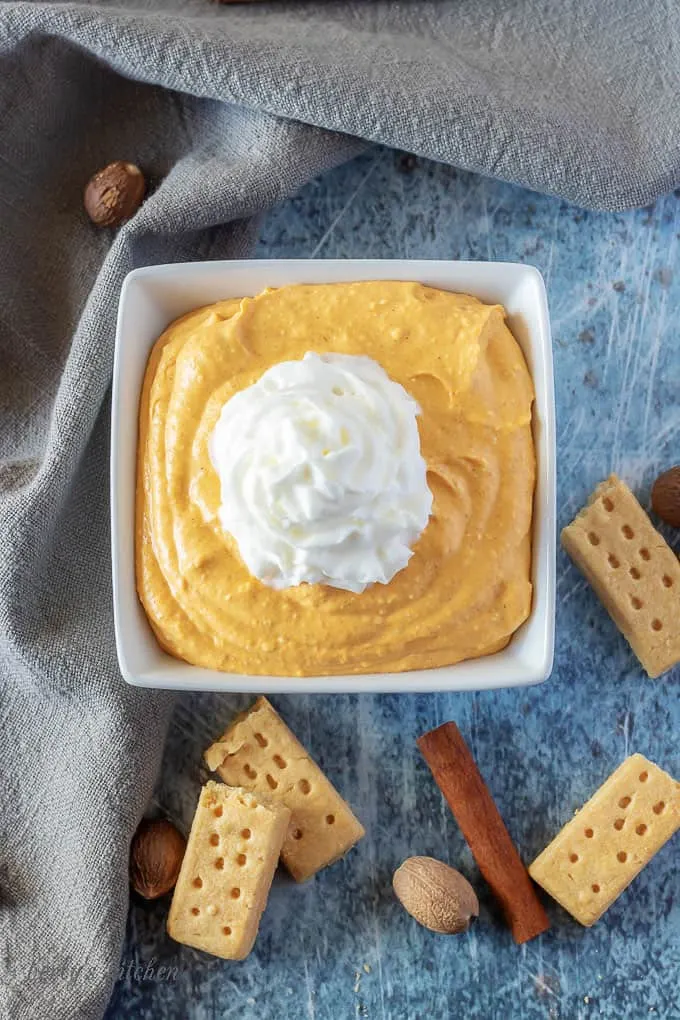 An aerial view of the finished pumpkin dip in a square bowl, topped with Ready Whip.
