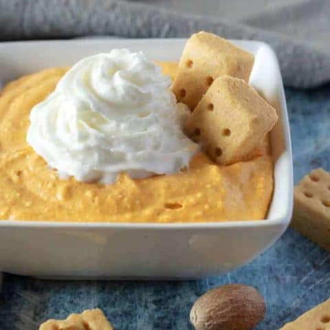 A close-up photo of the finished pumpkin dip with a shortbread cookie dipped into the dessert.