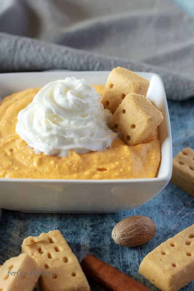 A close-up photo of the finished pumpkin dip with a shortbread cookie dipped into the dessert.