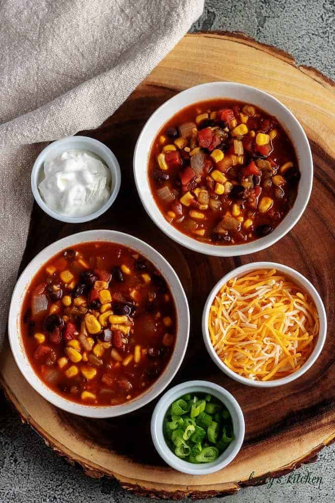 Another top-down photo of the chili with cheddar cheese, diced green onions, and sour cream.