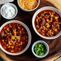 An aerial photo of the black bean chili served cheese, green onions, and sour cream on the side.