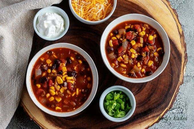 An aerial photo of the black bean chili served cheese, green onions, and sour cream on the side.