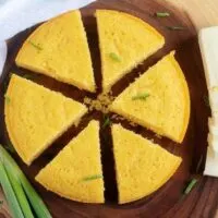 Arial view of buttermilk cornbread on a cutting board with green onion and butter.