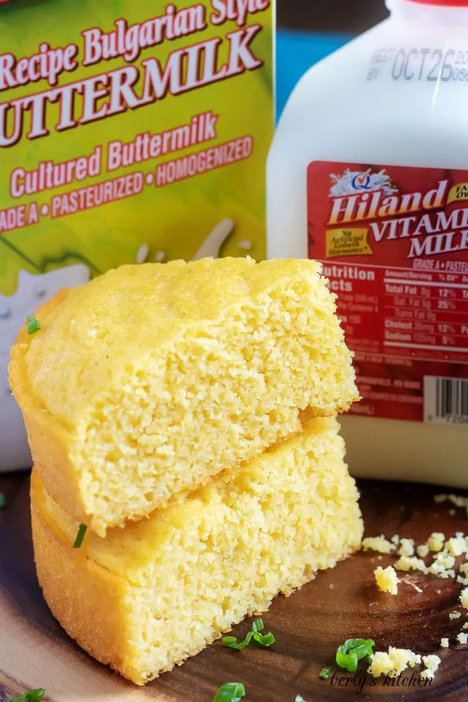 Two pieces of Instant pot cornbread stacked in front of Hiland buttermilk and Hiland whole milk.