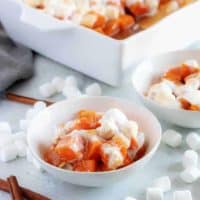 Candied sweet potatoes, sprinkled with marshmallows and served in little white bowls.