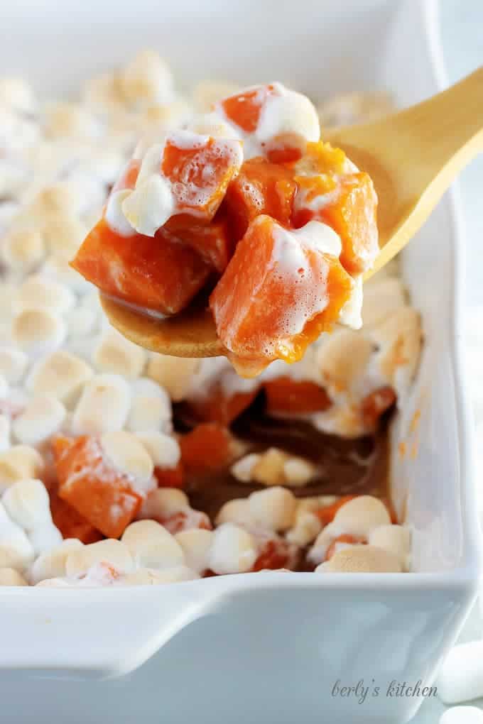 The candied sweet potatoes have cooked and are being scooped out with a spoon.