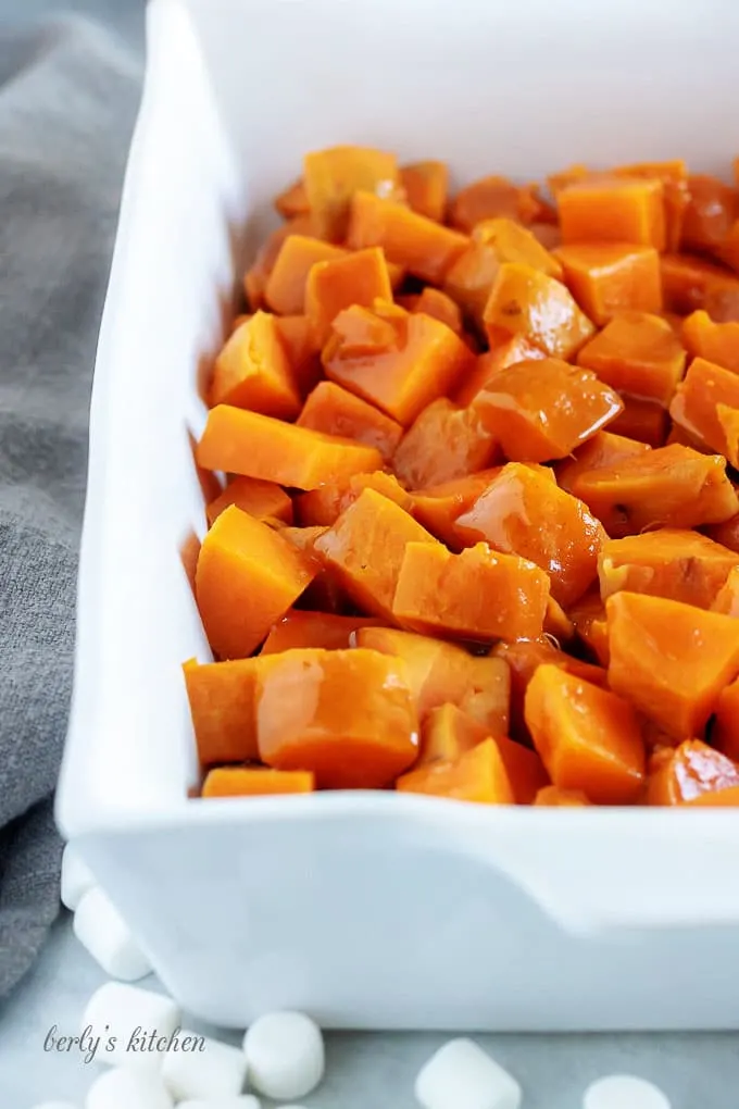 The candied sweet potatoes have been cut into cubes and placed into a large baking dish.