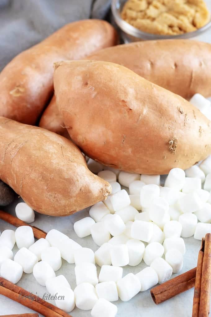 A close-up shot of the washed sweet potatoes, cinnamon sticks, and mini-marshmallows.