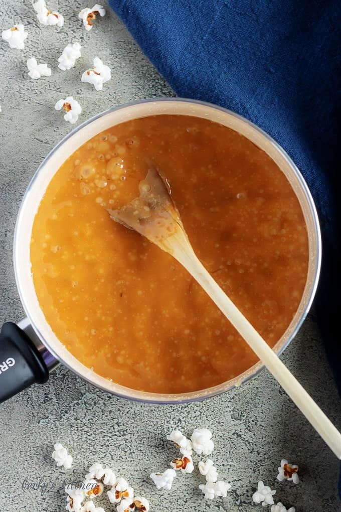 An aerial photo of the caramel sauce boiling in a saucepan with a wooden spoon.