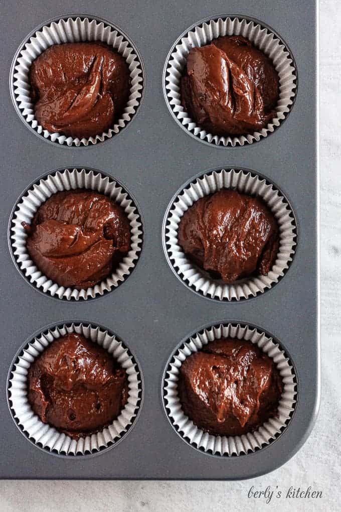 A top-down shot of the chocolate cupcakes batter poured into black cupcake liners.