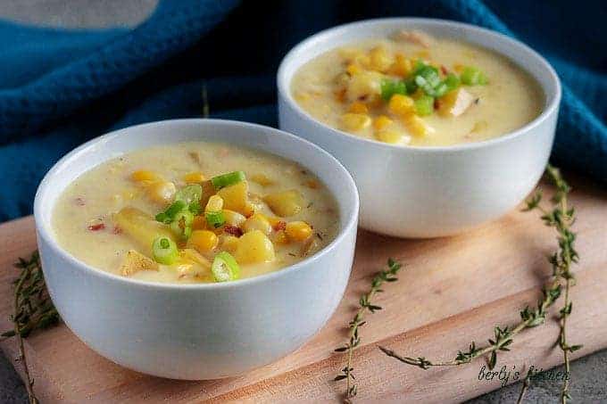 Two bowls of finished corn chowder with bacon served in simple white bowls.