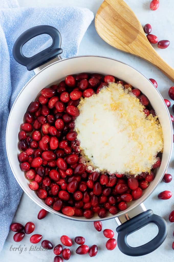 An aerial photo of the cranberries, sugar, and other ingredients in a large saucepan.