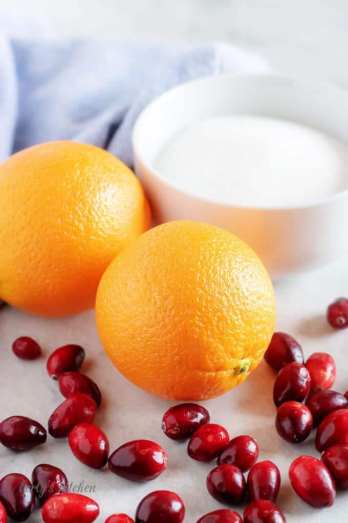 The orange cranberry sauce ingredients like fresh oranges, fresh cranberries, and sugar are in the photo.