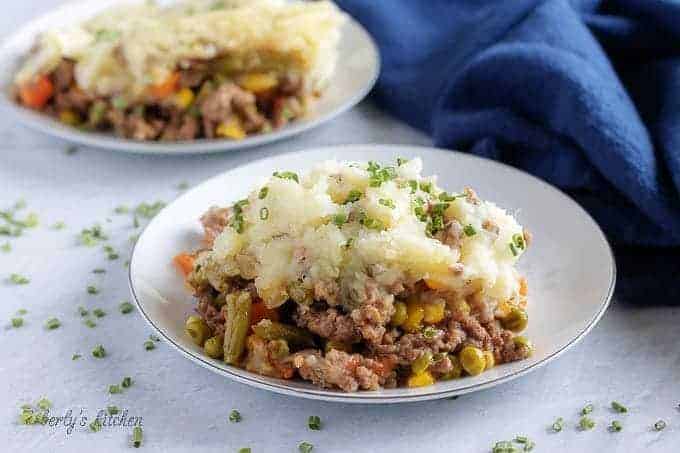 The finished shepherd's pie in a white plate showing the layers of mashed potatoes, veggies, and meat.