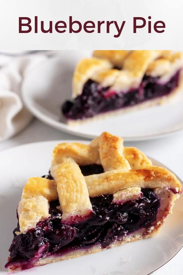 A large picture with two slices of the blueberry pie sitting on white pates.