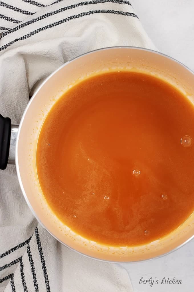 Top down view of a pan of melted caramel sauce used for bourbon caramel fudge.