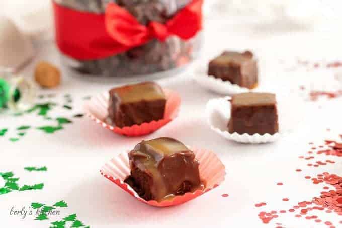 Several pieces of bourbon caramel fudge next to christmas confetti.